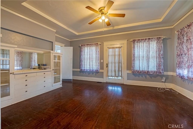 unfurnished living room featuring crown molding, a tray ceiling, dark wood-type flooring, and ceiling fan