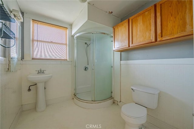 bathroom featuring walk in shower, toilet, and tile walls