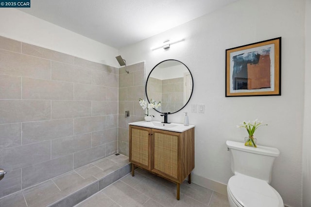 bathroom featuring tile patterned flooring, vanity, a tile shower, and toilet