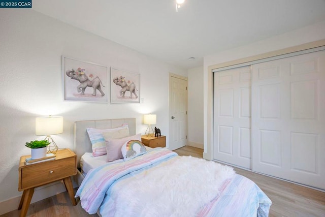 bedroom with light hardwood / wood-style floors and a closet