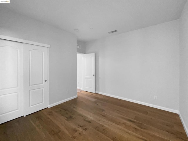 unfurnished bedroom with dark hardwood / wood-style flooring and a closet