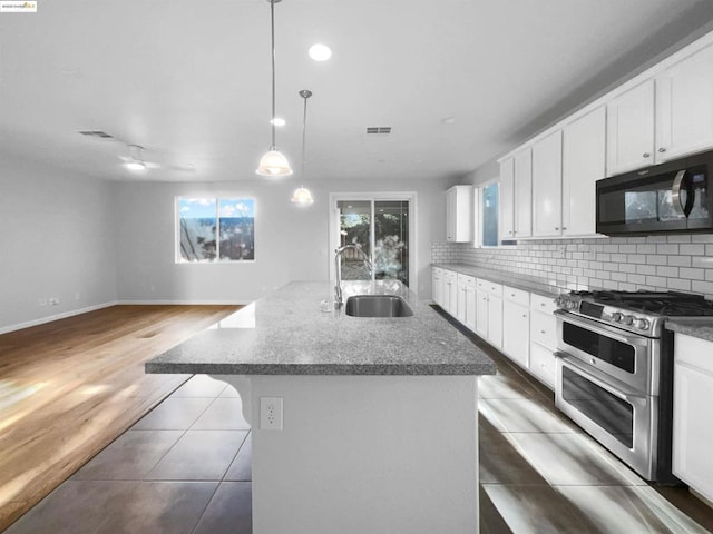 kitchen featuring sink, a center island with sink, pendant lighting, range with two ovens, and white cabinets