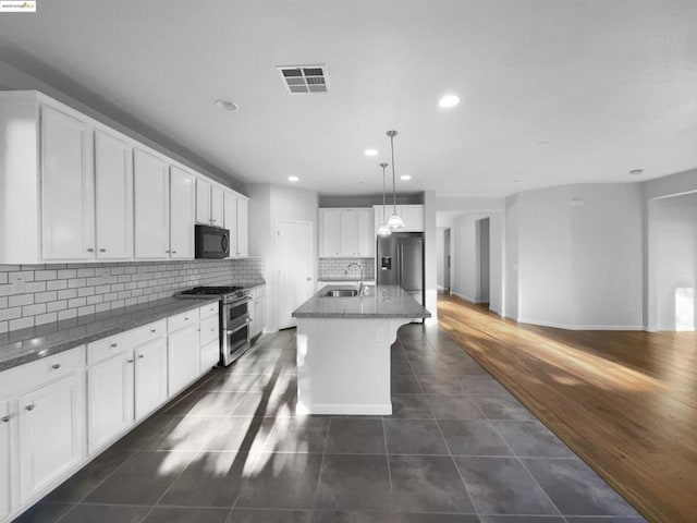 kitchen featuring sink, appliances with stainless steel finishes, white cabinetry, an island with sink, and decorative light fixtures