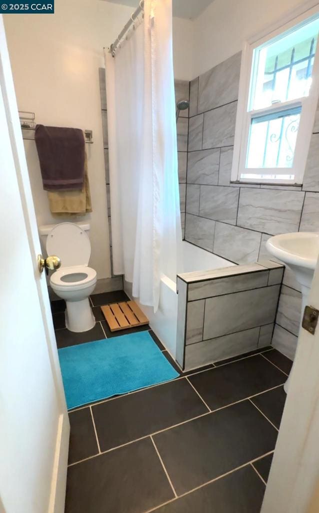 bathroom featuring shower / tub combo with curtain, tile patterned floors, and toilet