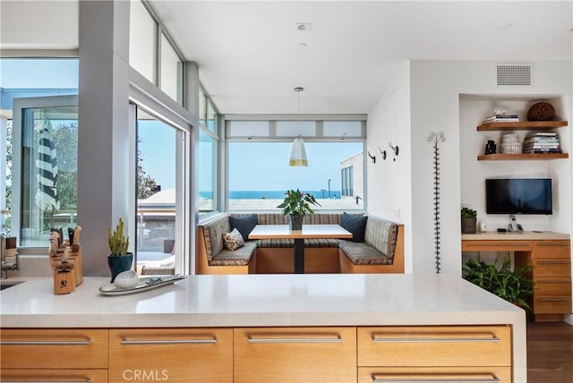 kitchen with a wealth of natural light, pendant lighting, light brown cabinetry, and breakfast area