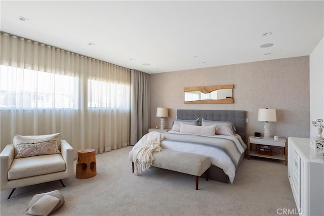 bedroom with wallpapered walls and light carpet