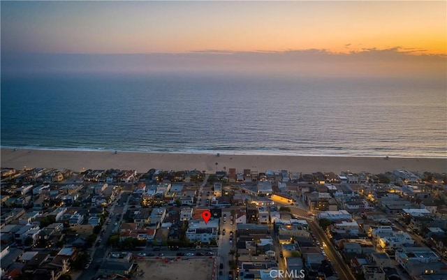 aerial view at dusk featuring a beach view and a water view