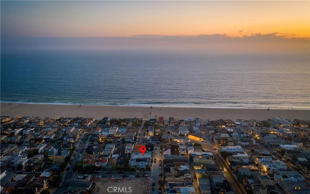 aerial view at dusk with a water view and a view of the beach