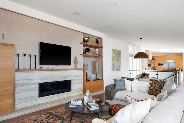 living room with hardwood / wood-style flooring, built in features, and a high end fireplace