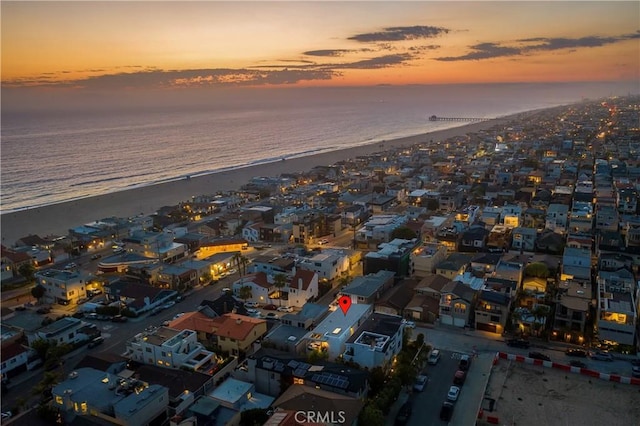 aerial view at dusk featuring a beach view and a water view