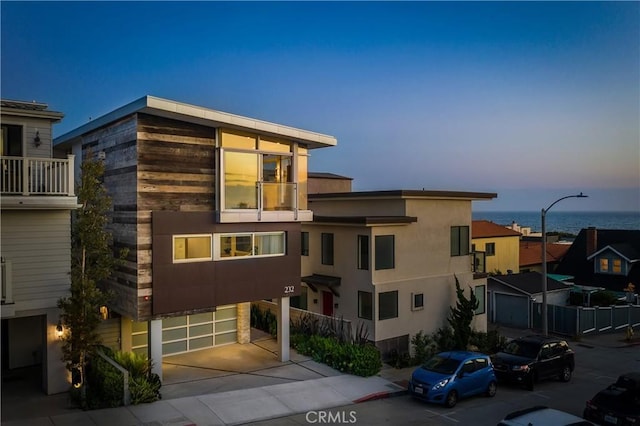 view of front facade featuring stucco siding, a water view, a garage, and driveway