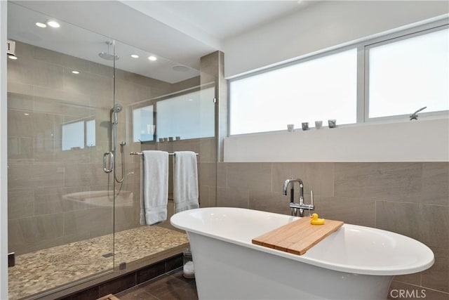 bathroom featuring plus walk in shower and tile walls