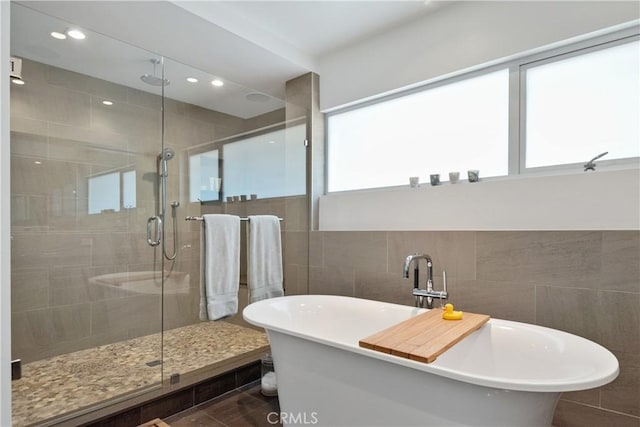 bathroom with tile walls, a soaking tub, recessed lighting, and a stall shower