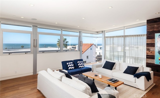 living area featuring recessed lighting, a water view, baseboards, and wood finished floors