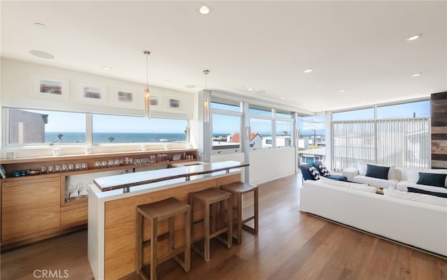 kitchen featuring a breakfast bar area, wood finished floors, recessed lighting, a sink, and hanging light fixtures