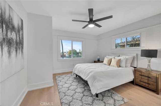 bedroom featuring multiple windows, light hardwood / wood-style floors, and ceiling fan