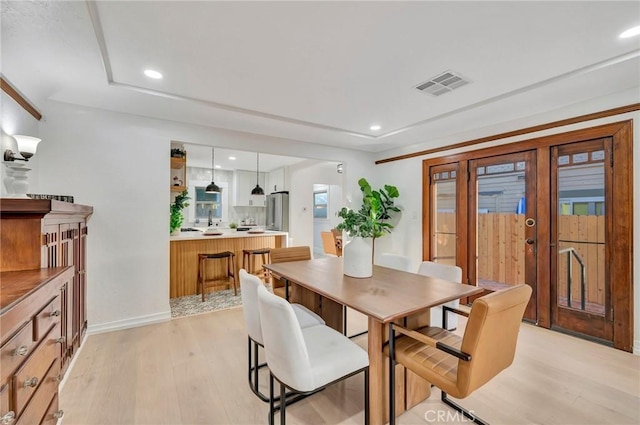 dining space featuring french doors, sink, and light hardwood / wood-style floors