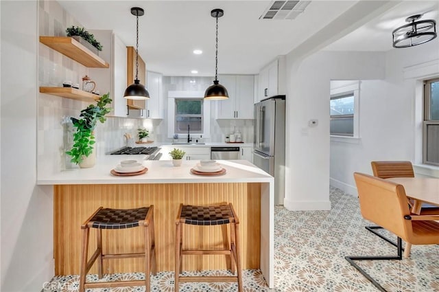 kitchen featuring appliances with stainless steel finishes, sink, a breakfast bar area, white cabinets, and kitchen peninsula