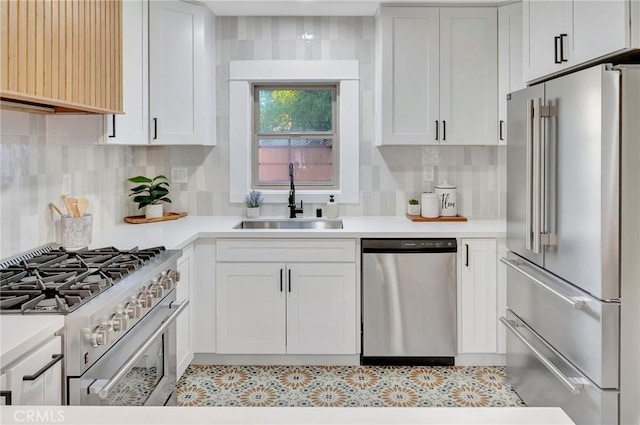 kitchen with high end appliances, sink, white cabinets, and backsplash