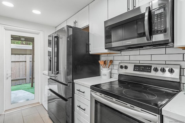 kitchen with stainless steel appliances, tasteful backsplash, and white cabinets