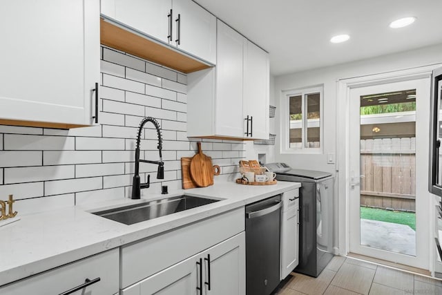 kitchen with sink, dishwasher, white cabinets, and light stone countertops