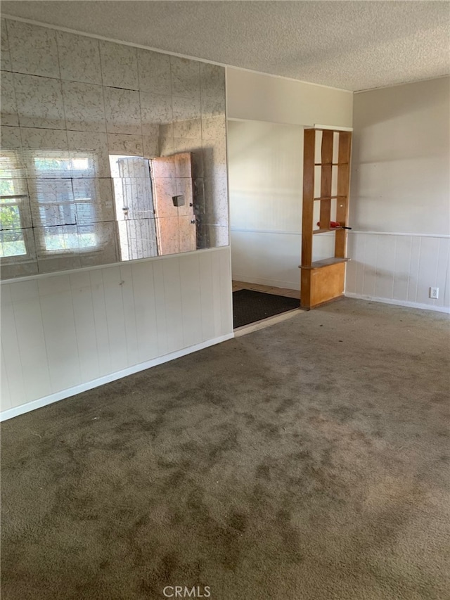 spare room featuring a textured ceiling and dark colored carpet