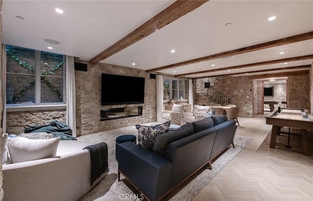 living room featuring light parquet floors, a stone fireplace, and beamed ceiling