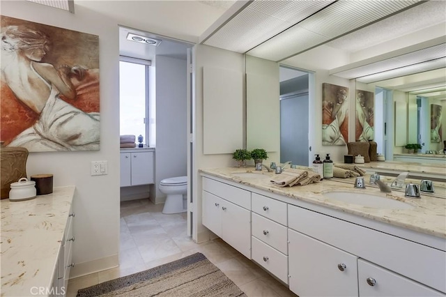 bathroom featuring double vanity, tile patterned floors, toilet, and a sink