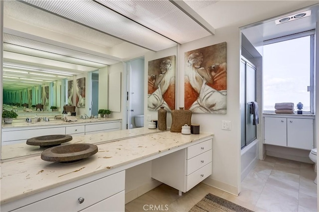 full bathroom featuring tile patterned floors, toilet, shower / bath combination with glass door, baseboards, and vanity