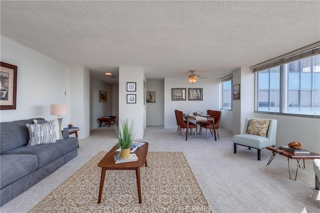 living room with light colored carpet, a textured ceiling, and a ceiling fan