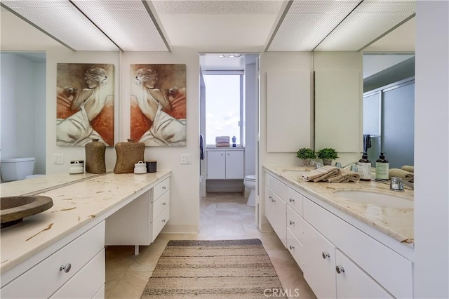 full bathroom featuring double vanity, tile patterned floors, toilet, and a sink