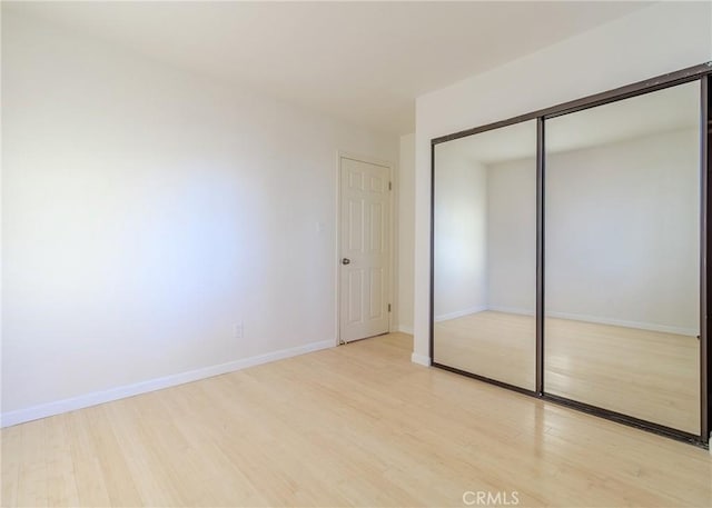 unfurnished bedroom with a closet and light wood-type flooring