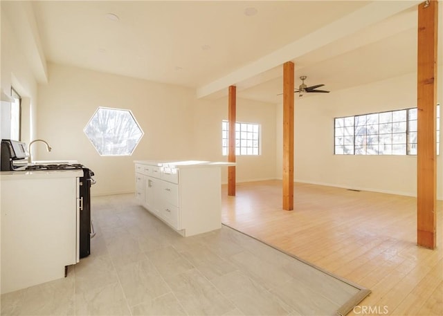 kitchen with ceiling fan, white cabinets, a kitchen island, range with gas cooktop, and light wood-type flooring