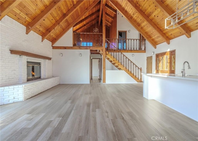 unfurnished living room featuring a fireplace, light hardwood / wood-style floors, sink, and wooden ceiling