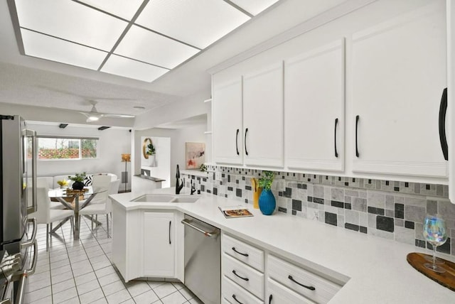 kitchen featuring sink, kitchen peninsula, stainless steel appliances, decorative backsplash, and white cabinets