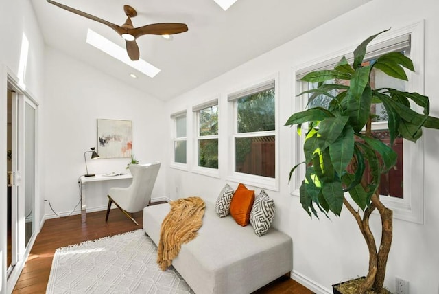 living area featuring hardwood / wood-style flooring, lofted ceiling with skylight, and ceiling fan