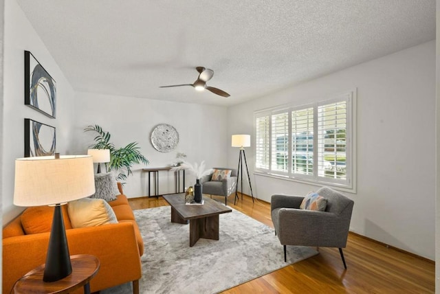 living room with ceiling fan, wood-type flooring, and a textured ceiling