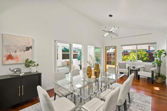 dining area with high vaulted ceiling, dark wood-type flooring, and a chandelier