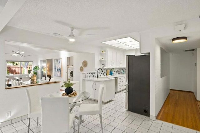 kitchen with sink, ceiling fan, white cabinetry, stainless steel appliances, and decorative backsplash