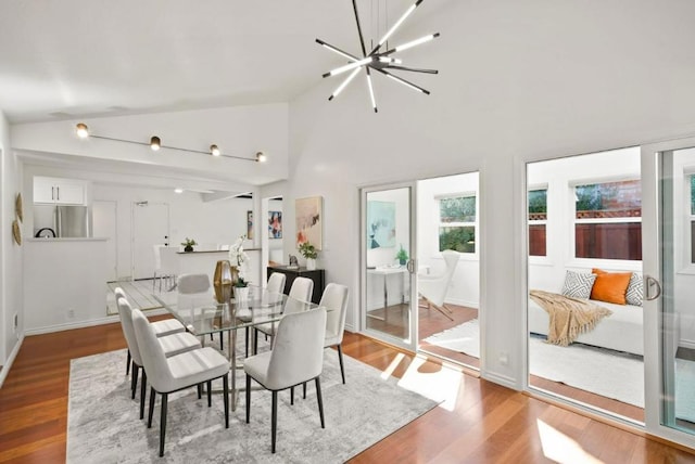 dining space with high vaulted ceiling, a notable chandelier, and light wood-type flooring