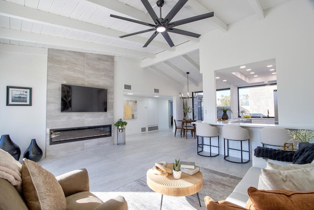 living room featuring a tiled fireplace, lofted ceiling with beams, and ceiling fan