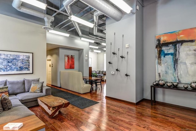 living room with dark wood-type flooring and a high ceiling