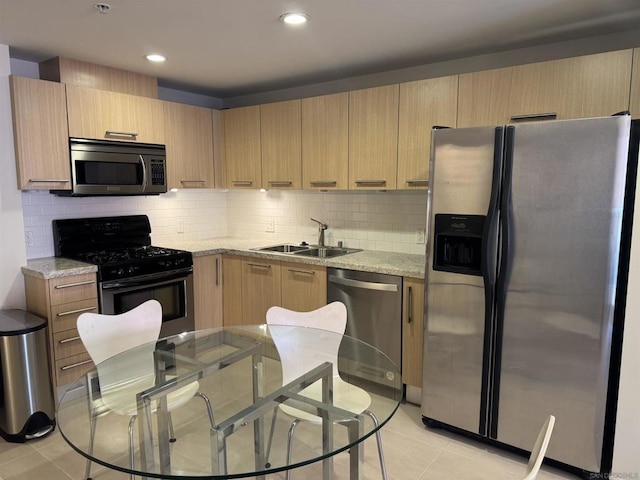 kitchen with sink, light stone counters, light brown cabinets, light tile patterned floors, and appliances with stainless steel finishes