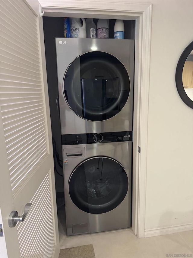 laundry room featuring stacked washing maching and dryer and tile patterned floors