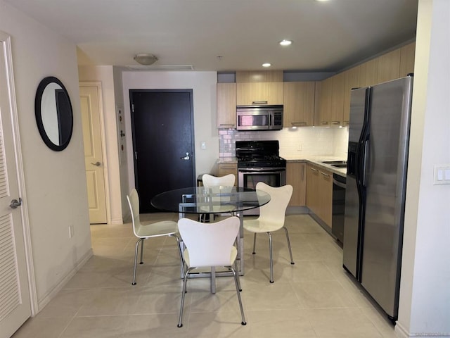 kitchen featuring appliances with stainless steel finishes, light tile patterned floors, light brown cabinetry, and decorative backsplash