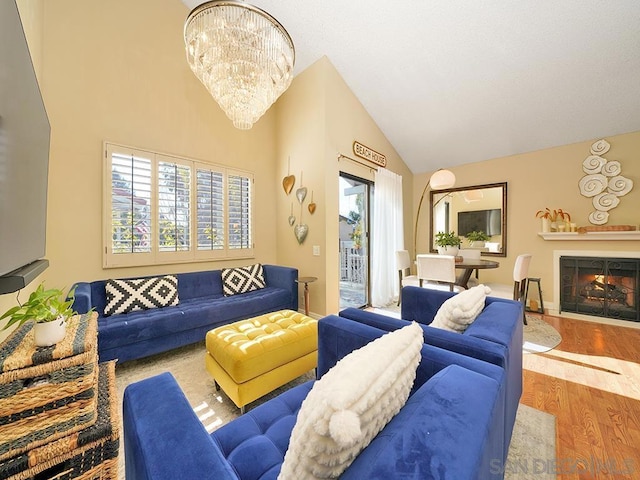 living room featuring an inviting chandelier, wood-type flooring, and high vaulted ceiling