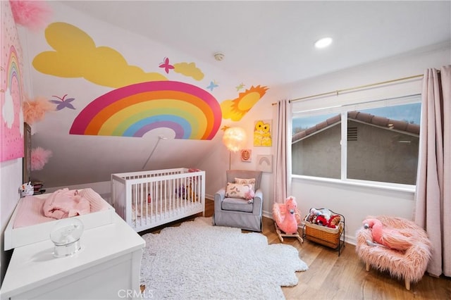 bedroom featuring hardwood / wood-style flooring and a nursery area