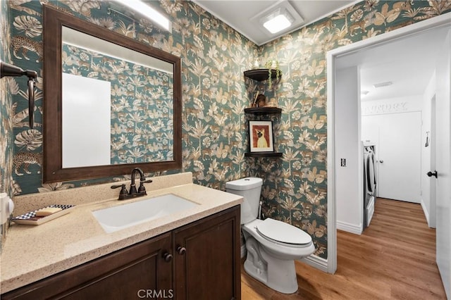 bathroom with hardwood / wood-style flooring, vanity, toilet, and separate washer and dryer