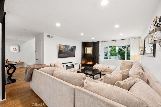 living room with a brick fireplace and light hardwood / wood-style flooring