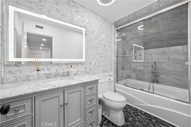 full bathroom with enclosed tub / shower combo, vanity, and toilet